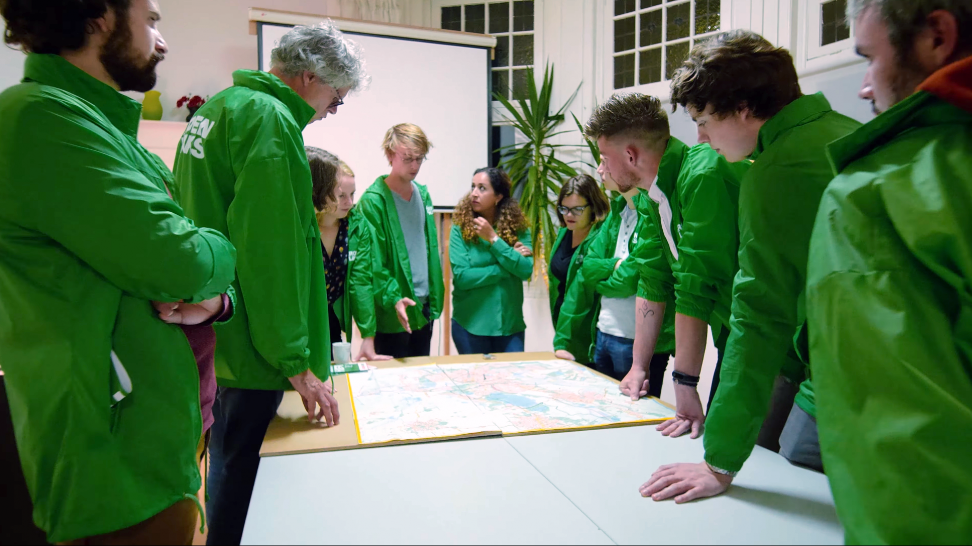 mensen met GroenLinks jasjes in overleg